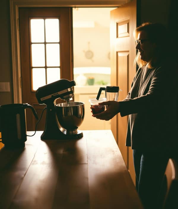 A neighbor lending a stand mixer and blender at a warm home entrance